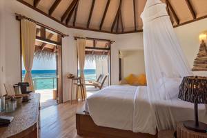 Schlafzimmer im Drift Thelu Veliga Retreat mit Blick auf das Meer und Möbeln auf der Terrasse.