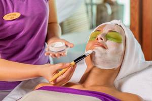 Frau im Hurawalhi Island Resort Spa wird mit einer Gesichtsmaske behandelt.