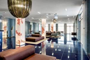Lobby des Cala Ponte Hotels mit modernen Möbeln und einer großen Kronleuchter
