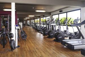 Innenbereich des Fitnesscenters des Papagayo Beach Hotel & Resort Curaçao mit vielen Geräten und Holzboden