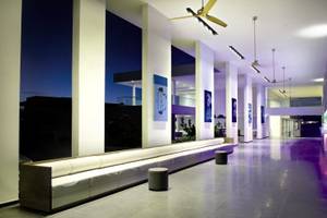 Der Eingangsbereich des Papagayo Beach Hotel & Resort mit einem langen weißen Sofa, violetten Boden und großen Kunstwerken an der Wand.