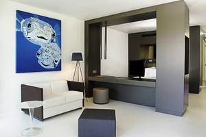 Innenansicht der Suite im Papagayo Beach Hotel & Resort Curaçao mit weißem Sofa, Schreibtisch und Fernseher.