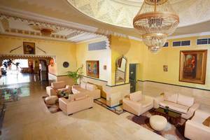 Lobby des Pickalbatros Alf Leila Wa Leila Resorts mit gelben Wänden, Kristallleuchtern und Sofas.
