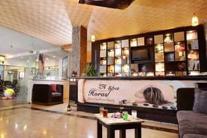 Lobby des Pickalbatros Alf Leila Wa Leila Resorts mit Couch, Tisch und Wellness-Werbetafel.