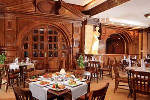 Innenansicht des Restaurants des Pickalbatros Alf Leila Wa Leila Resorts mit holzvertäfelten Wänden, Statuen und gedeckten Tischen.