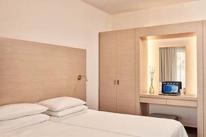 Schlafzimmer im Atlantica Mikri Poli Kos Hotel mit zwei Betten, einem Laptop auf dem Schreibtisch und einer Lampe.