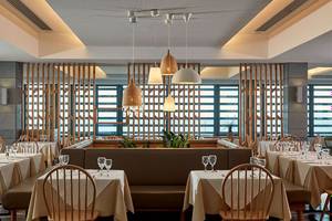 Restaurantbereich des Atlantica Mikri Poli Kos Hotels mit Tischen, Stühlen und Fenstern.