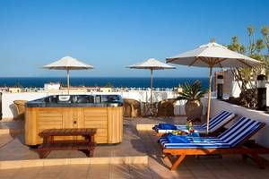 Terrasse im Seaside Sandy Beach Hotel mit Hot Tub und Sonnenschirmen am Meer