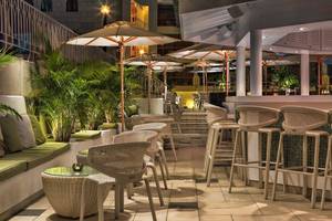 Terrasse des Seaside Sandy Beach Hotels mit Stühlen, Tischen und Schirmen bei Nacht