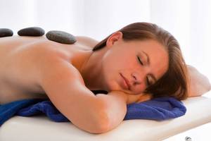 Eine Frau genießt eine Rückenmassage mit Steinen im Seaside Sandy Beach Hotel.