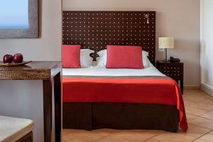 Ein Hotelzimmer von Seaside Sandy Beach mit einem Bett, zwei roten Kissen und einer roten Bettdecke.