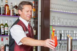 Ein Barkeeper im Zora Hotel bereitet Cocktails hinter der Bar zu.
