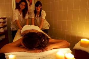 Eine Frau genießt eine Massage im Spa des Zora Hotels, während zwei Therapeutinnen sie betreuen.