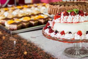 Verschiedene Desserts im Zora Hotel auf einer Glasplatte serviert, einschließlich einer Torte mit Früchten und Sahne.