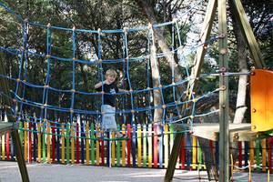 Ein junger Junge klettert an einem Netz in einem Spielplatz im Freien im Zora Hotel.