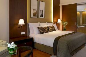 Schlafzimmer im Anantara Riverside Bangkok Resort mit Bett, Lampen und Möbeln.