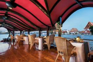 Essensbereich des Anantara Riverside Bangkok Resorts mit Blick auf den Fluss und abendlicher Dekoration.