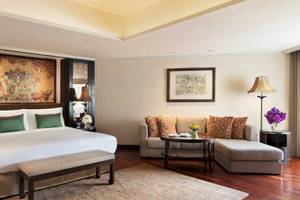 Ein elegantes Zimmer im Anantara Riverside Bangkok Resort mit einem großen Bett, einem Sofa und einer Tischlampe.
