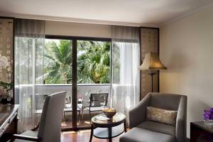 Innenansicht eines Zimmers im Anantara Riverside Bangkok Resort mit Schreibtisch, Stühlen und großem Fenster mit Balkon.