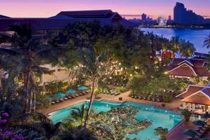 Außenansicht des Anantara Riverside Bangkok Resorts mit Swimmingpool, Loungebereich und Blick auf die Skyline.