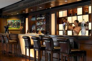 Hotelbar im Anantara Riverside Bangkok Resort mit Barkeeperin und voller Bar.