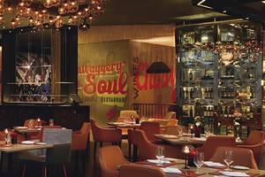 Innenraum des Mövenpick Hotel Jumeirah Beach Restaurant mit bunten Wandmalereien, Tischdekoration und hängenden Kronleuchtern.