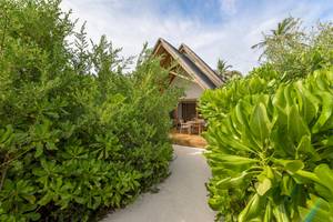 Außenansicht des Fushifaru Maldives Hotels mit einer kleinen Hütte und einem Tisch im Freien.