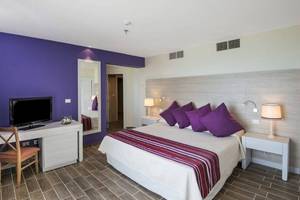 Blau Varadero Hotelzimmer mit violetten Wänden, Bett und Fernseher.