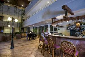Ein Paar sitzt an der Bar des Blau Varadero Hotels, mit einem Klavier und einer Lampe im Hintergrund.