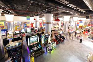 Übersicht über die Spielhalle im Sueno Hotels Deluxe Belek mit verschiedenen Arcade-Spielen und Gästen, die spielen und herumlaufen.