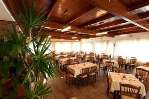 Innenansicht des Restaurants im Atlantica Marmari Beach Hotel mit gedeckten Tischen und Stühlen.