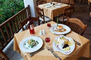 Tisch im Restaurant des Atlantica Marmari Beach Hotel mit Tellern, Wein und Dekoration.