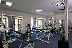 Fitnessstudio im Atlantica Marmari Beach Hotel mit verschiedenen Geräten und blauem Boden.