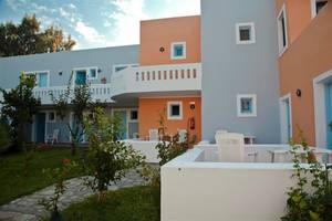 Außenansicht des Atlantica Marmari Beach Hotels mit orange und blau gestrichenen Wänden und weißen Möbeln im Freien.