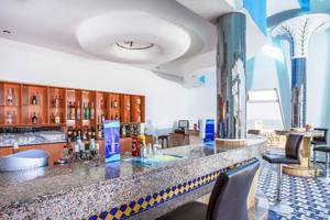 Die Bar im Atlas Amadil Beach Hotel mit Granittheke und blau-gelbem Bodenmuster.