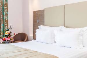 Atlas Amadil Beach Hotel Schlafzimmer mit Bett, Kissen, Blumen und Stuhl