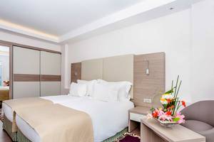 Schlafzimmer im Atlas Amadil Beach Hotel mit zwei Betten, weißen Kissen und einem Nachttisch mit Blumenvase.