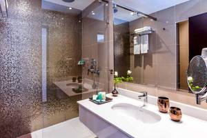Badezimmer des Atlas Amadil Beach Hotels mit Glasdusche, Waschbecken und Spiegel.