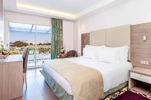 Innenansicht eines Hotelzimmers im Atlas Amadil Beach Hotel mit einem Bett, einem Schreibtisch und einem Balkon
