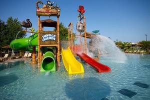 Wasserpark im Atlantica Holiday Village Kos mit drei bunten Rutschen und einem Wasserfall.