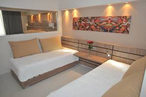 Doppelbettzimmer im Atlantica Holiday Village Kos mit modernen Möbeln und Kunstwerk an der Wand.