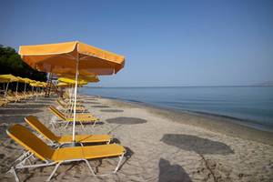 Strand mit gelben Sonnenliegen und Sonnenschirmen am Atlantica Holiday Village Kos