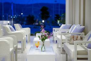 Loungebereich des Atlantica Holiday Village Kos mit weißen Möbeln und Blick auf einen Hafen.