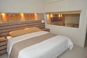Ein Schlafzimmer im Atlantica Holiday Village Kos mit einem Bett, zwei Nachttischen und einem großen Fenster.