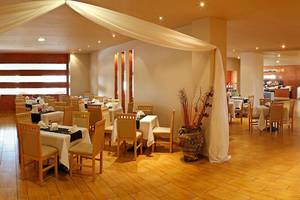Innenbereich des Restaurants im Atlantica Holiday Village Kos mit gedeckten Tischen und Stühlen.
