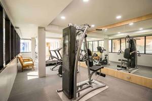 Fitnessraum im Chaba Samui Resort mit verschiedenen Geräten und Fenstern.