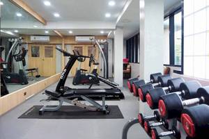 Fitness-Center im Chaba Samui Resort mit Laufbändern, Hanteln und einer Glaswand.