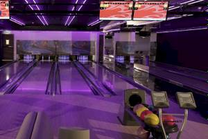 Kempinski Hotel Muscat Bowlinghalle mit Bowlingbahnen und lila Beleuchtung.