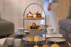 Empfangsbereich des Kempinski Hotels Muscat mit einer Auswahl an Desserts auf einem dreistöckigen Serviertablett.