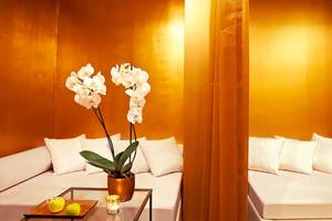 Interieur des Grecotel Meli Palace mit gelben Wänden, weißen Kissen und einer Orchidee auf dem Tisch